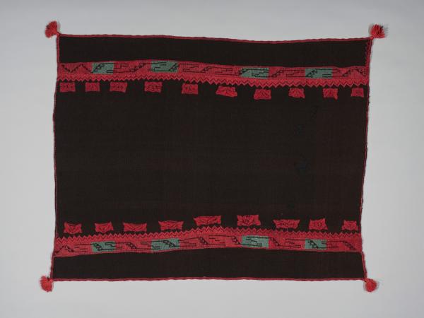 An Acoma textile that is black with red and gray graphic designs on the top and bottom