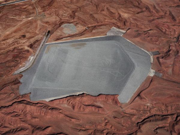 Landscape photograph of a rock area with a large gray uranium deposit in the center that resembles a lake