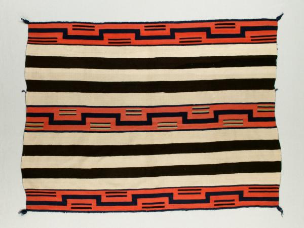 Red, black, and cream colored striped blanket designed by a Navajo artist