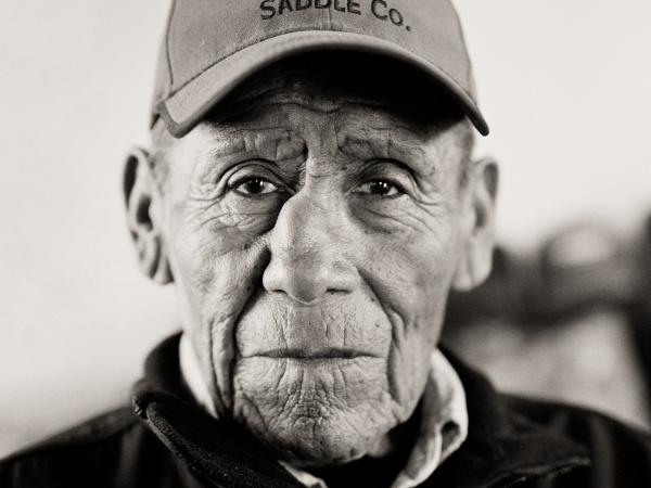 Black and white photograph of an older Native American gentleman wearin a baseball cap