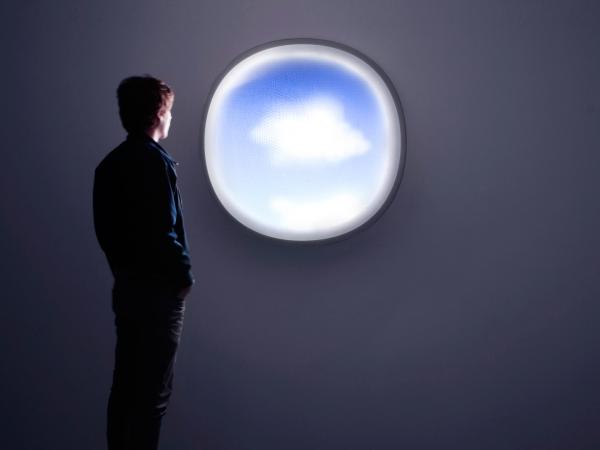 Man looking out a circular cloud-shaped window