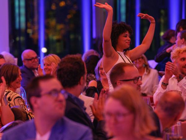 Woman raising her hands to the roof in a large crowd of people cheering