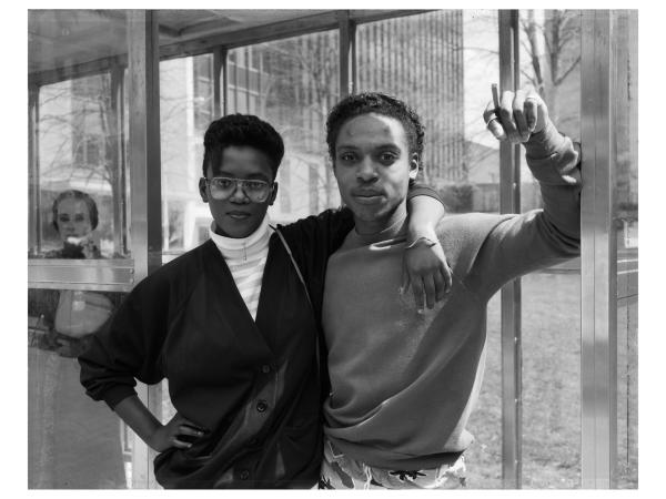 A young black couple embracing at a bus stop station