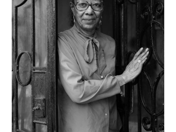 An older black woman in glasses standing in a doorway
