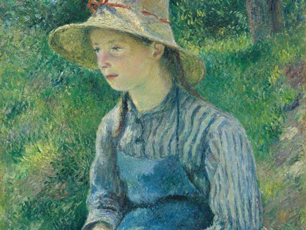 Young girl sitting down hands folded in lap wearing a straw hat
