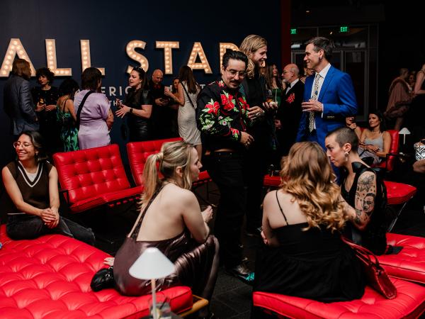 Group of well-dressed partygoers standing, sitting, and mingling