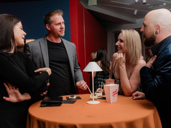 Two men and women mingling over a table at last year's ball