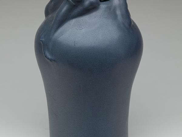 Clay pot with a crouching human figure wrapped around the spout