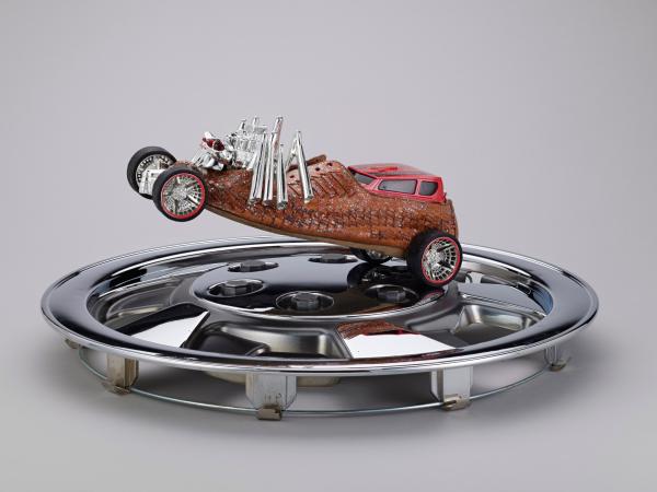 Mixed media sculpture of a car racing on a silver hubcap