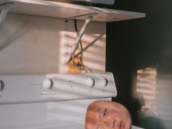 Surreal photograph of severed head resting on a kitchen stovetop