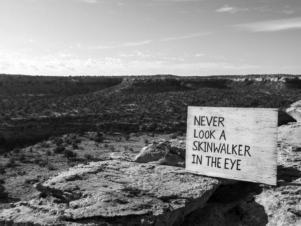 Black and white landscape with a sign that reads, "never look a skinwalker in the eye"