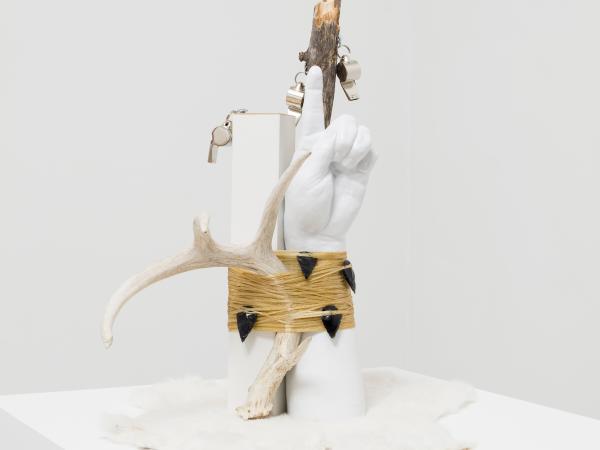 Artwork sculpture installation with a tied pair of hands pointing up toward the sky