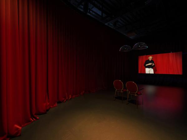 Projection screen in a red-curtained room with two chairs