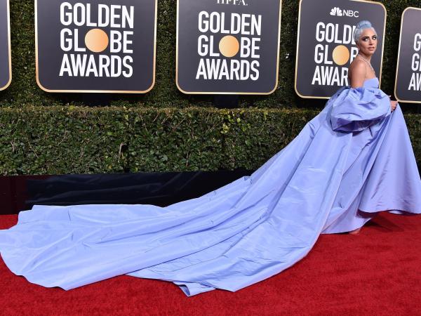 Lady Gaga wearing a pale blue gown with a long trail at the Golden Globes awards red carpet