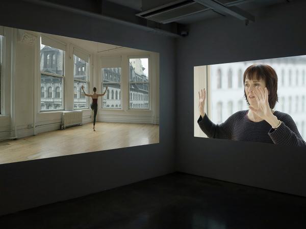 Two projection screens featuring a woman dancing and another woman holding her hands up