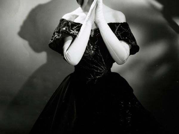 Black and white photograph of opera singer Maria Callas, in an elegant black ball gown