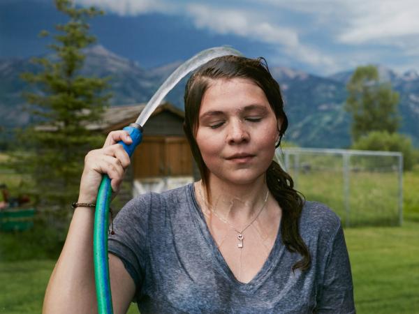 Woman spraying water on herself from a hose