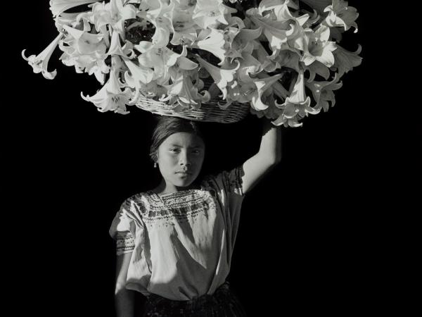 Woman holding a large basket of flowers on her head