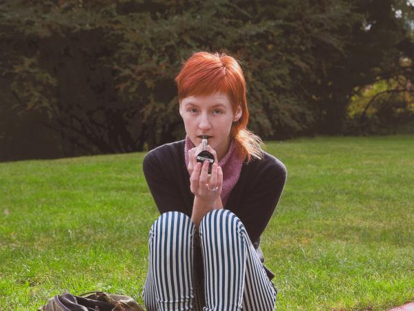 Androgynous woman with red hair sitting on a street curb