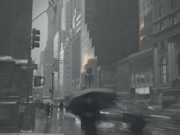 Man walking the New York City streets under an umbrella on a rainy day