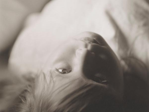 Woman lying down head first on a bed