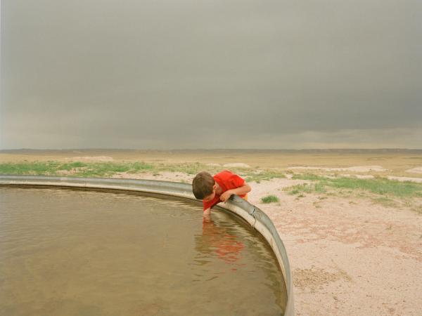 Young boy reaching his hand into a pool of water