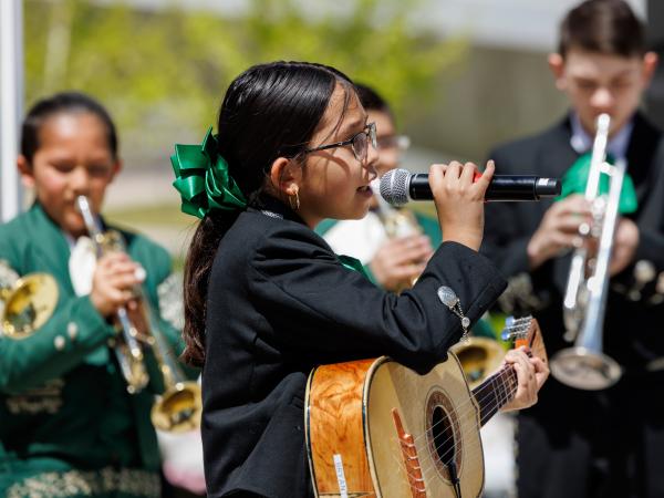 Young girl performing guitar and singing at Dia del Nino
