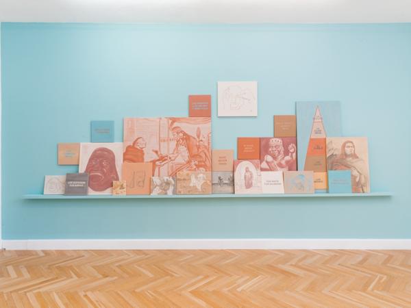 Wall view of several square-sized paintings leaning against a wall