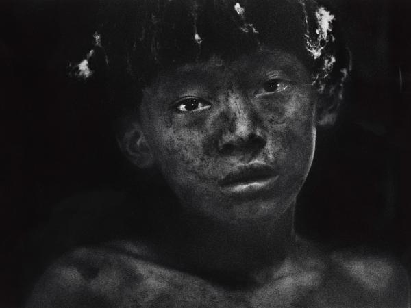 Young boy with soot or dirt on his face staring straight into the camera