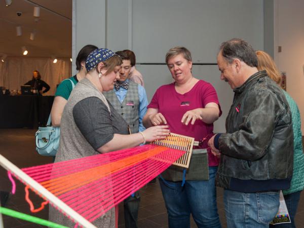 artist demonstrating yarn art to guests at Untitled Final Friday