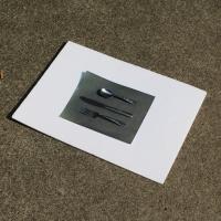 A piece of paper with silver kitchen cutlery at the center