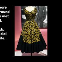 Sleeveless, tea length dress made of black silk with a yellow lace overlay.