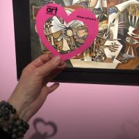 A hand holding a paper heart in front of the artwork, “L’ecartele (El descuartizado)” by Gunther Gerzso.