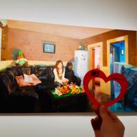 Hand holding a paper heart in front of the artwork, "She—White Collar Worker" by Yu Hong