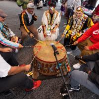 Group of men in a circle performing on a drum