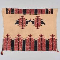 an Acoma Pueblo textile with red and black and green graphic designs embroidered on in