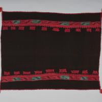 An Acoma textile that is black with red and gray graphic designs on the top and bottom