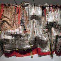 Hanging installation of a large blanket-like tapestry made out of bottle tops and copper wire