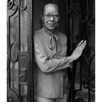 An older black woman in glasses standing in a doorway