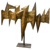 Gold geometrical sculpture resembling a bird with outstretched wings
