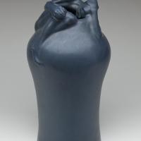 Clay pot with a crouching human figure wrapped around the spout