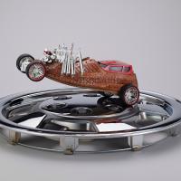 Mixed media sculpture of a car racing on a silver hubcap