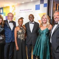 Group of well-dressed adults posing for the camera at a black-tie event