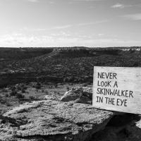 Black and white landscape with a sign that reads, "never look a skinwalker in the eye"