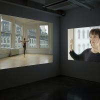 Two projection screens featuring a woman dancing and another woman holding her hands up