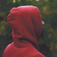 African American man in a red hoodie facing away from the camera