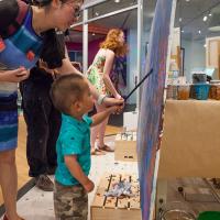 A mother helping a child paint at the Denver Art Museum on Free First Saturday.