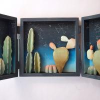 A diorama triptych featuring cut outs of cacti and the night sky