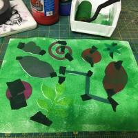 Green tempera paint is applied to the paper using a foam roller.