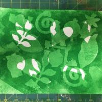 Overlapping green and white shapes are created on the paper.